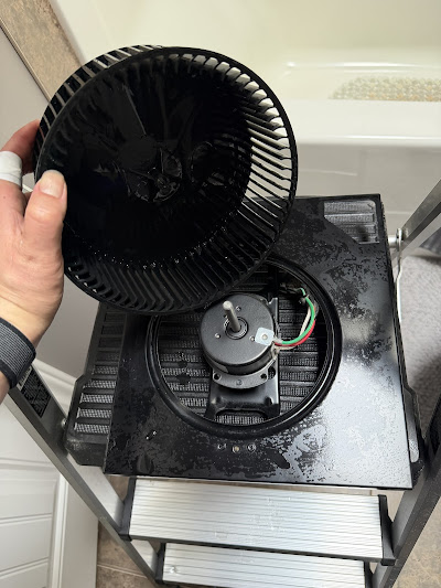 Cleaned bathroom exhaust fan motor and blower wheel on a ladder