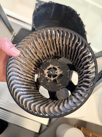 Centrifugal blower wheel caked with dust and lint before cleaning